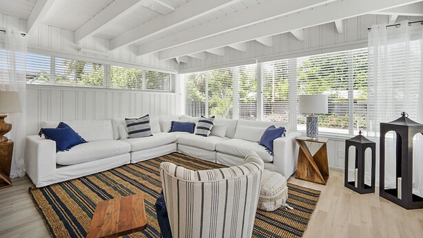 Una sala moderna con un sofá modular blanco, un sillón a rayas y una alfombra estampada.