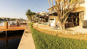 A waterfront property with a pool, outdoor seating, and a view of the water.