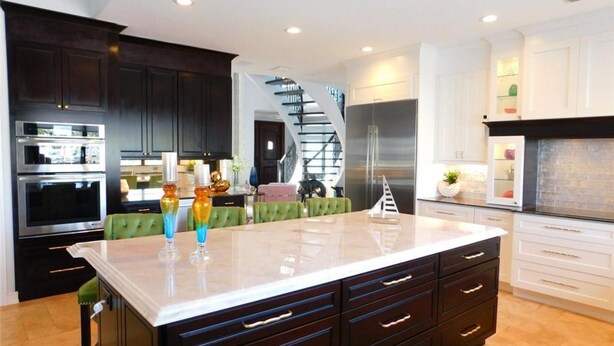 A modern kitchen with dark cabinetry, a central island, and stainless steel appliances.