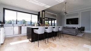 A modern kitchen with a central island, bar stools, and a large window.