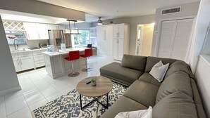 A modern living room with a sofa, a coffee table, and a kitchen area in the background. - Walk to Fort Lauderdale Beach - Perfect Beach Escape (Fort Lauderdale)