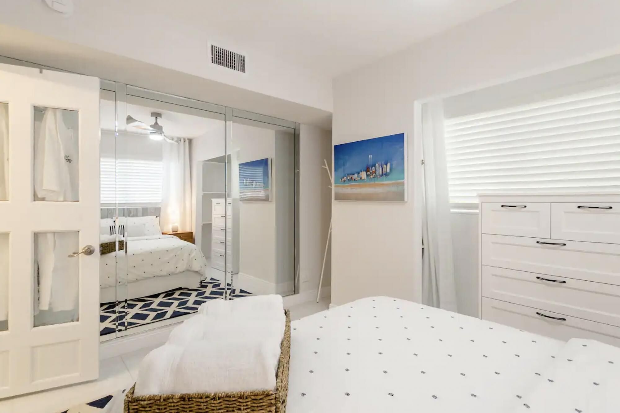 A bedroom with a bed, a wardrobe, a dresser, and a mirror.