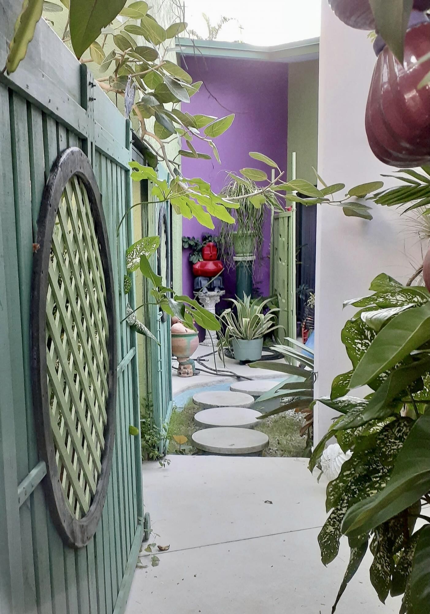 A courtyard with a green fence, potted plants, and a purple wall.