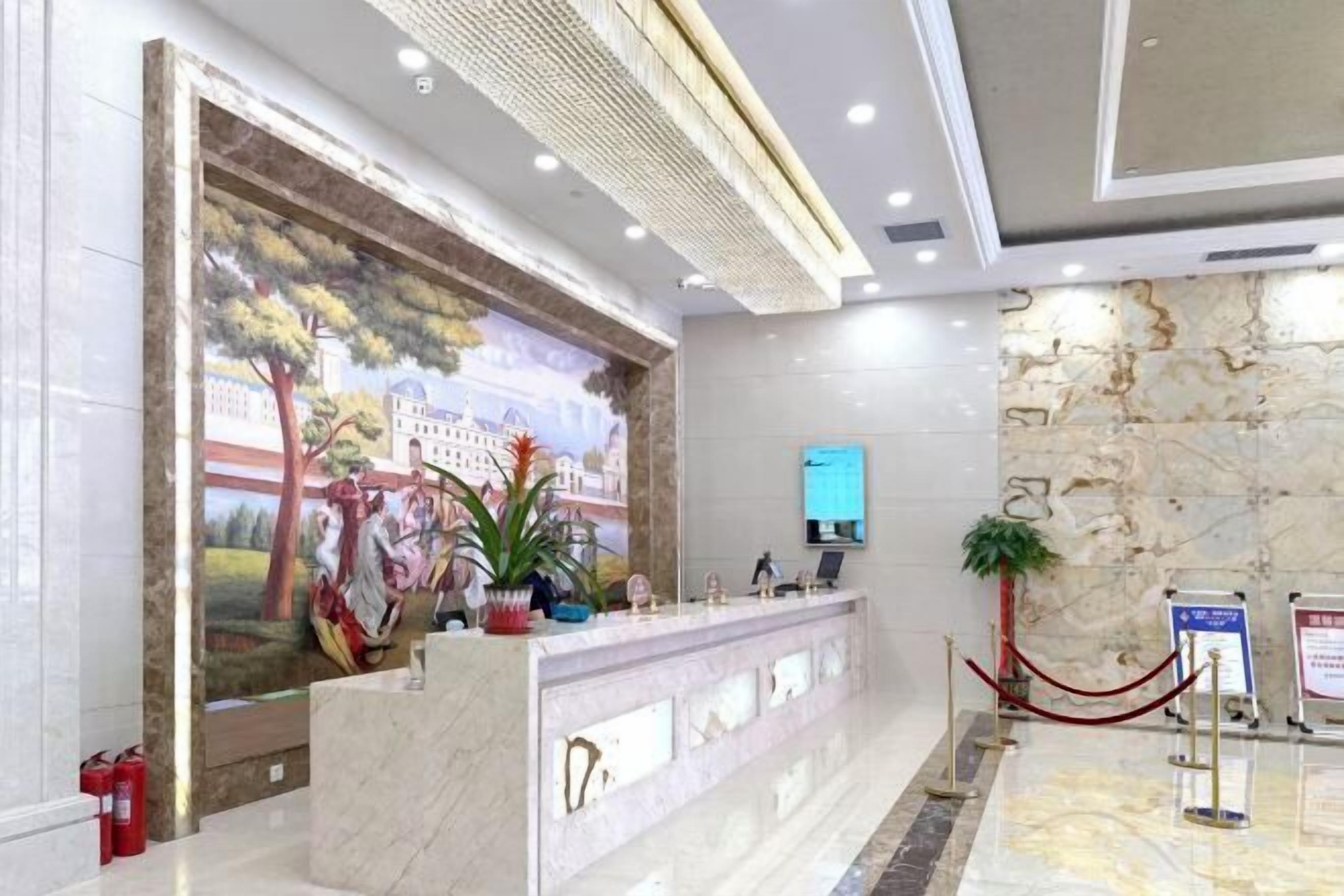 A hotel reception area with a marble counter, a mural on the wall, and a modern ceiling design.
