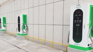 Een rij oplaadpunten voor elektrische voertuigen, met een groen en wit kleurenschema, aangesloten op een stroombron.