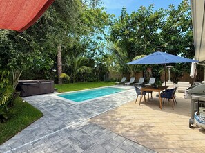 A swimming pool with a tiled deck, surrounded by lush greenery and a barbecue area with outdoor furniture. - AVAILABLE NOW!! FERN COTTAGE! FREE beach parking! Weekly/Monthly/Yearly Rentals! (Naples)