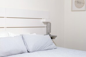 Ein ordentlich bezogenes Bett mit gestreifter Bettwäsche und einem Kopfteil mit horizontalen Linien.