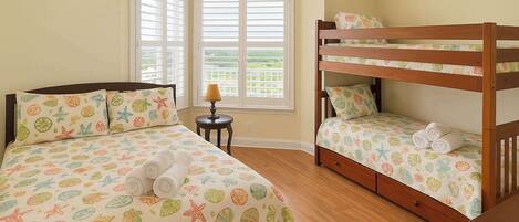 A bedroom with two beds, one with a bunk bed, and a small table with a lamp.