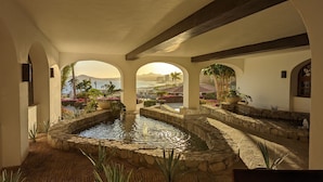 A courtyard with a central water feature, stone walls, and arches.