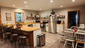 A modern kitchen with a central island, bar stools, a refrigerator, and a coffee station. - Secluded Cabin Getaway with Firepit (Greenfield)
