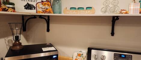 A kitchen with a microwave, a toaster, and a blender. There is a sign on the wall that reads "Mutton Creek Getaway".