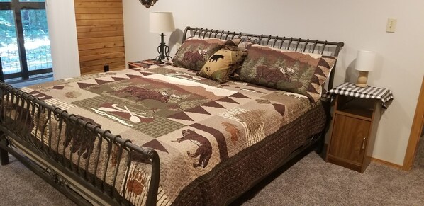 A bed with a patterned quilt, a wooden headboard, and a small bedside table with a lamp. - Secluded Cabin Getaway with Firepit (Greenfield)