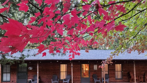 A cozy cabin-style building with a porch, wooden exterior, and a sign welcoming guests. - Secluded Cabin Getaway with Firepit (Greenfield)