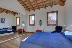 Quarto com uma cama grande, um espelho, uma escrivaninha e uma cadeira.