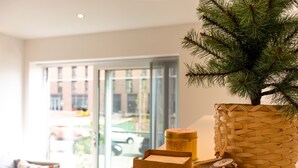A room with a large window, a woven basket, a box, and a small tree. - Livestay - 1bed Apt Private Building Free Parking (Luton)