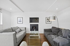 A modern living room with two grey sofas, a glass coffee table, and a floor lamp.
