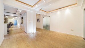 En modern inredning med trägolv, infälld belysning och en hall som leder till ett rum med en garderob och en affisch på väggen.
