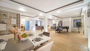 Ett rymligt vardagsrum med ett matbord för fyra personer, ett piano och en soffa.