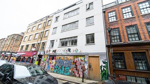 A multi-story building with a white facade and a colorful graffiti-covered wall. - Exquisite 2400sqft 3 Bed Brick Lane Pad (London)