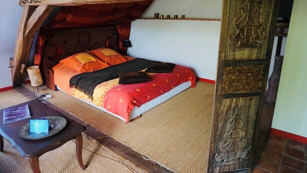 Een gezellige kamer met een bed, een tafel met een dienblad en een decoratief houten paneel.
