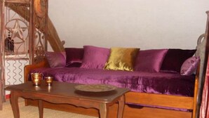 Een kamer met een paarse bank, een houten salontafel en een decoratieve metalen poort.