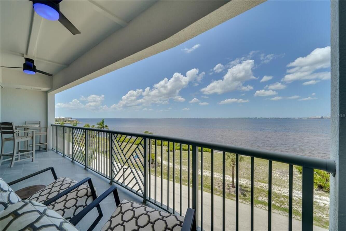Un balcon avec vue sur la mer, un ventilateur de plafond et du mobilier d’extérieur.