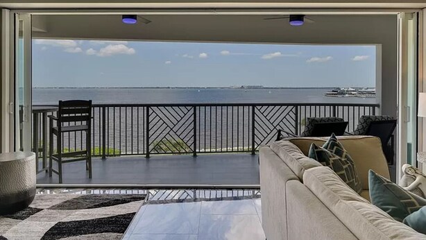 Een balkon met uitzicht op zee, een bank, een stoel en een tapijt met een patroon.