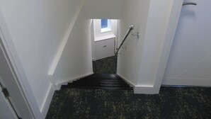 Eine schmale Treppe mit Handlauf, die zu einer Empore mit Fenster führt.