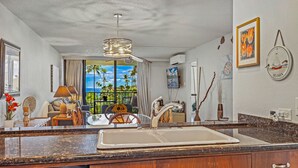 Una cocina con una isla grande, un comedor con vistas y un área de estar con un amplio ventanal con vista al océano.