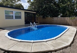 A rectangular swimming pool with a white deck and a ladder, surrounded by a wooden fence and trees. - Pool Home, Sleeps 8, Hollywood Beach | Near Hard Rock, Monthly Stays Welcome (Hollywood)