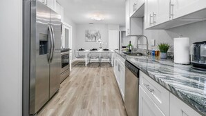 A modern kitchen with stainless steel appliances, white cabinetry, and a marble countertop. - Renovated Home in Hollywood (Hollywood)