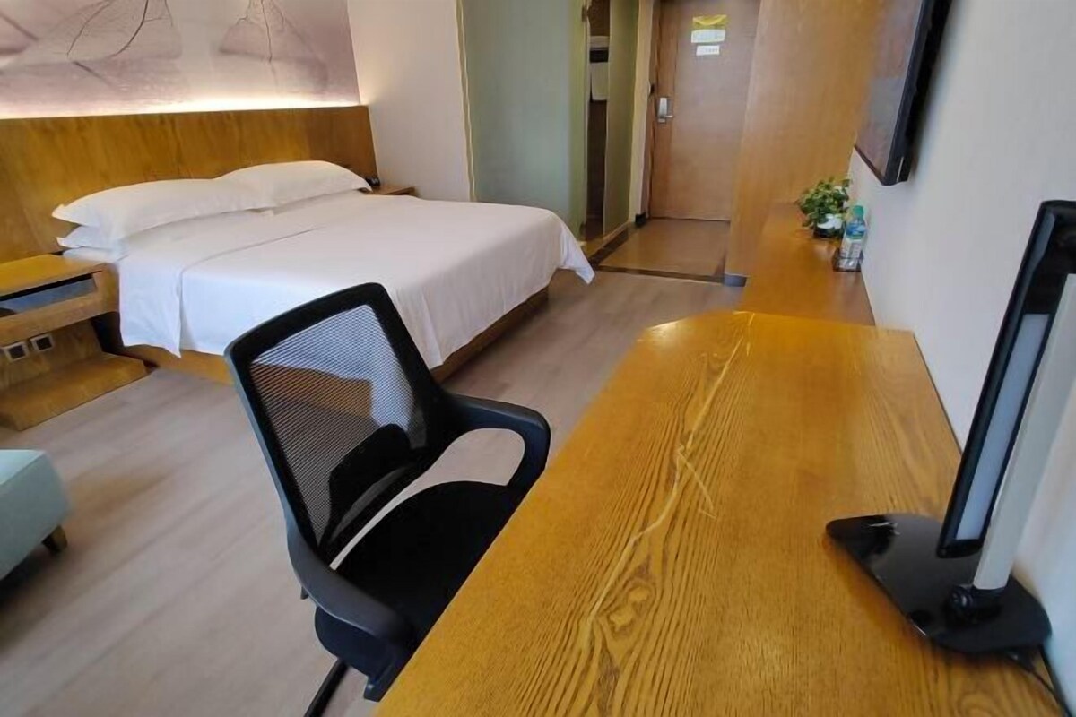 Ein Hotelzimmer mit einem Bett, einem Schreibtisch mit Computer und einem Sessel.