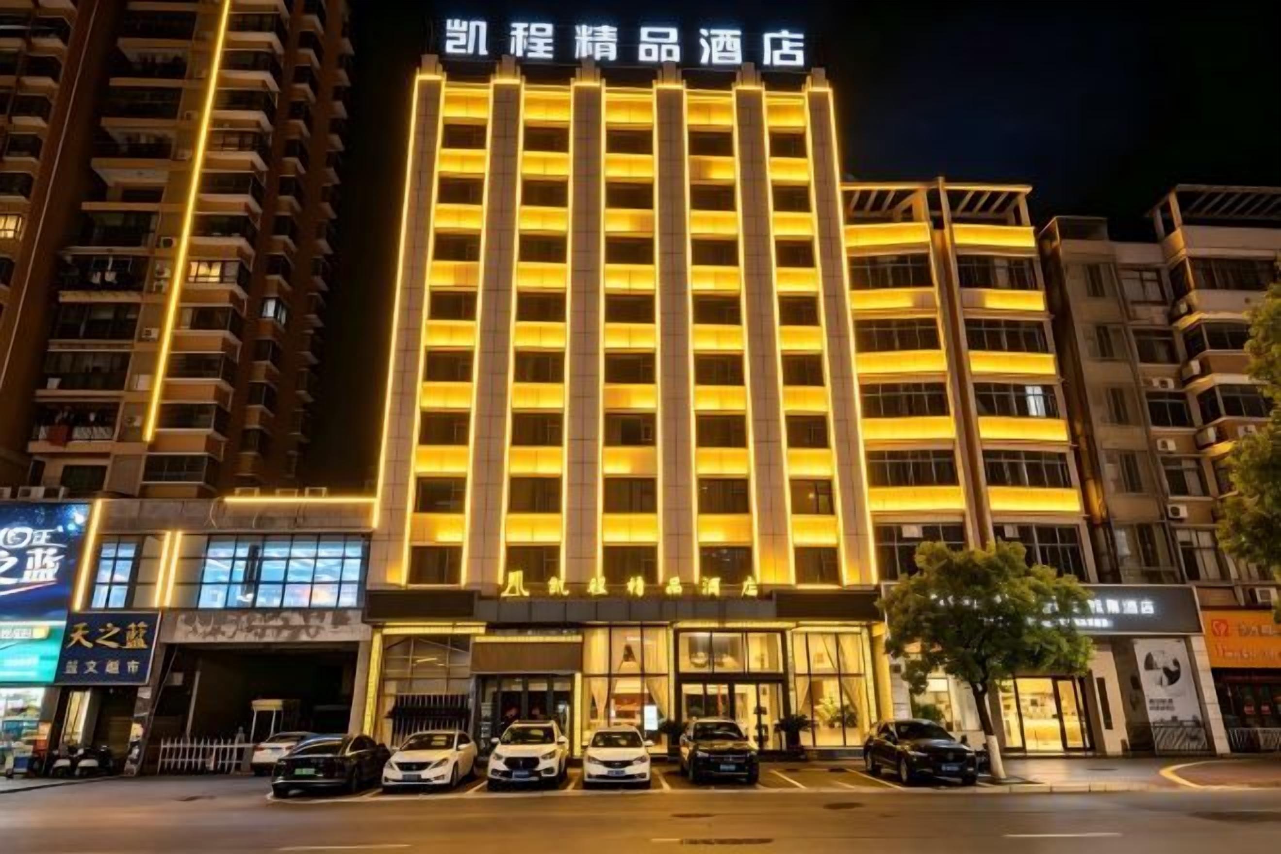 Un hotel con un letrero llamativo, varios pisos y un estacionamiento al frente.