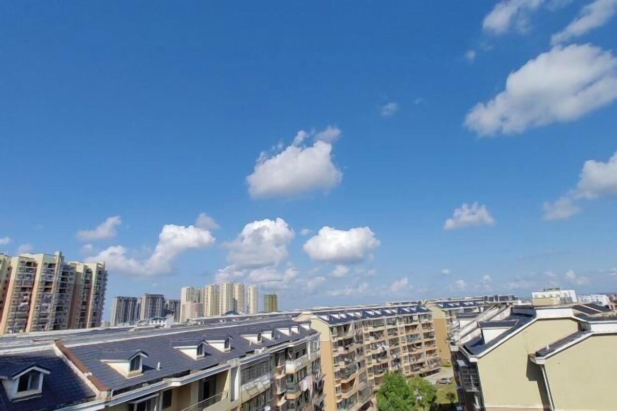 Ein Wohngebiet mit mehrstöckigen Wohnhäusern, wolkenlosem Himmel und vereinzelten Wolken.