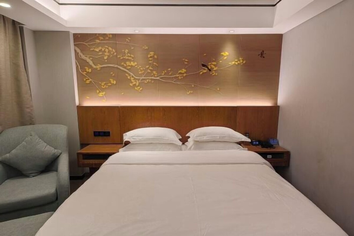 Ein modernes Hotelzimmer mit einem großen Bett, einem Nachttisch, einem Sessel und einer dekorativen Wandverkleidung.