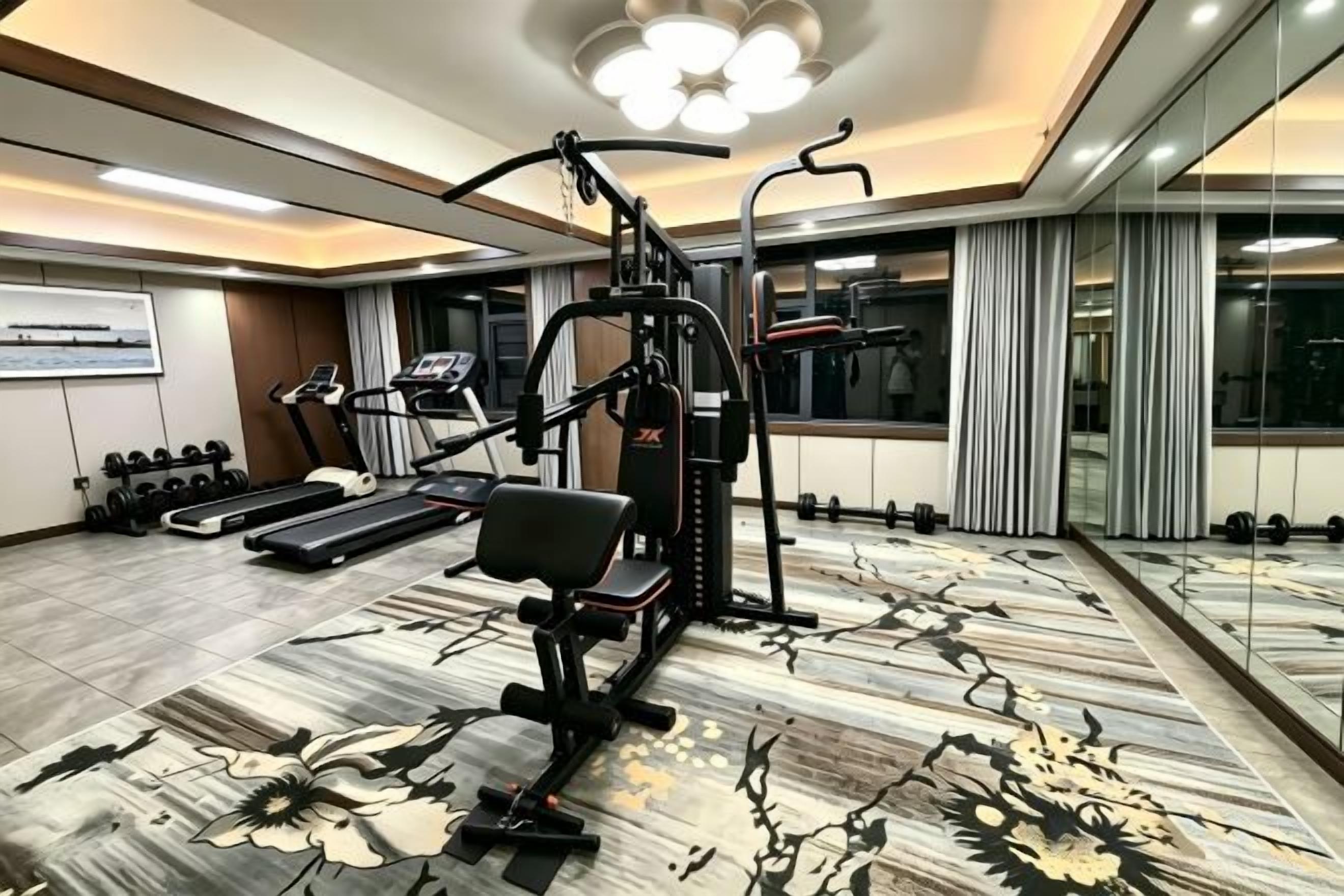 A hotel gym with exercise equipment, a treadmill, and a mirror wall.