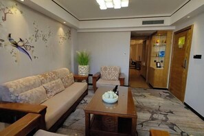 Ein Wohnzimmer mit Sofa, Sesseln, einem Couchtisch und einer Wandmalerei.