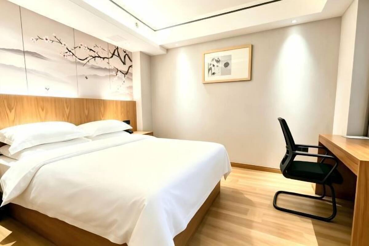 Quarto de hotel com cama, escrivaninha e cadeira.