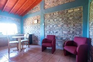 Ein Zimmer mit Backsteinwand, Holzboden und einem Tisch mit Stühlen sowie einem Fenster.