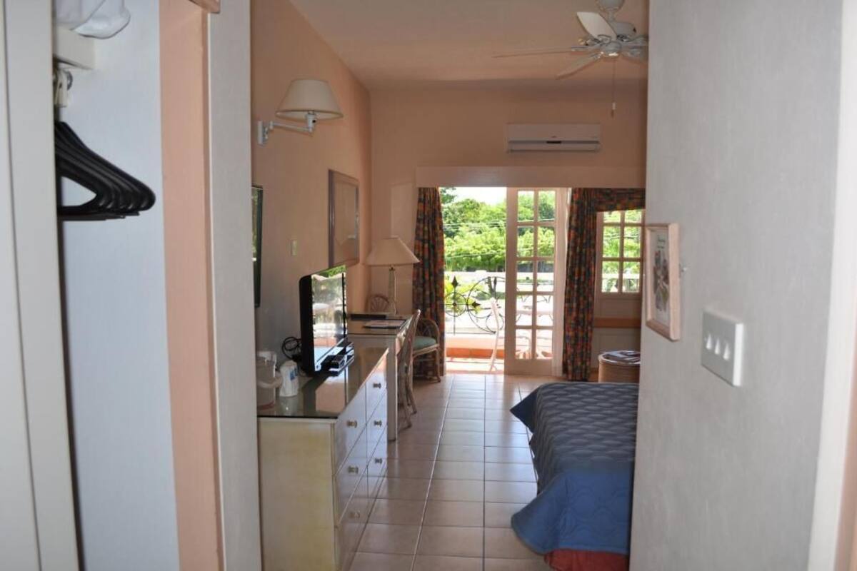 A hotel room with a bed, a desk, a chair, a TV, and a window with curtains.