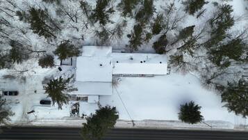 A snow-covered building with a flat roof, surrounded by trees and a road.