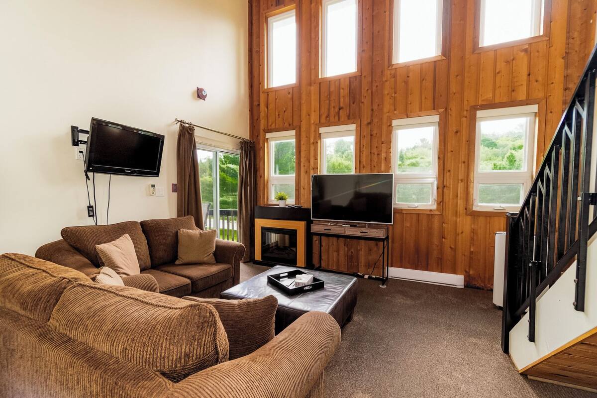 A living room with a brown sofa set, a flat-screen TV, and a fireplace.