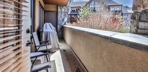 A balcony with a covered seating area, stone walls, and a view of neighboring houses.