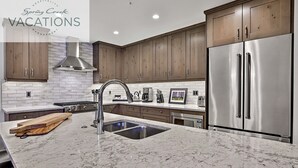 Una cocina moderna con encimeras de mármol, electrodomésticos de acero inoxidable y muebles de madera.
