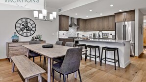 Una cocina moderna con armarios de madera, un refrigerador de acero inoxidable y una isla central con taburetes de bar.