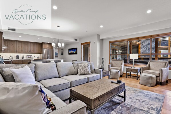 A modern living room with a sectional sofa, a coffee table, and a dining area with chairs.