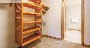A room with a wooden shelving unit against the wall, a door leading to another room, and a small rug on the floor.