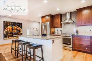 A modern kitchen with wooden cabinets, stainless steel appliances, and a central island with bar stools.