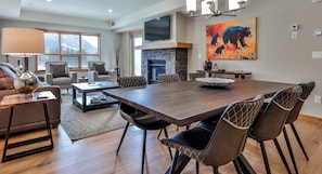 Amplia sala de estar con una gran mesa de comedor, asientos cómodos, chimenea y televisor.