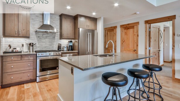 A modern kitchen with wooden cabinets, stainless steel appliances, and a central island with bar stools.